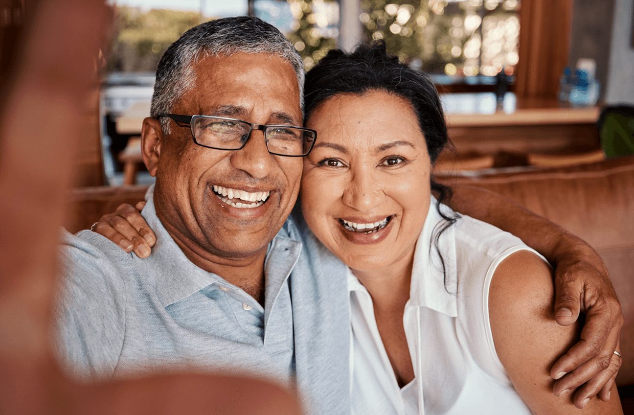 Two people smiling closely together in a warm, sunlit living room.