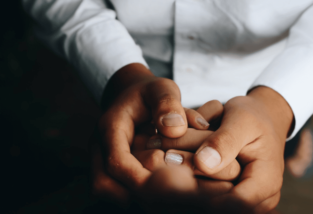 Clinician in a white shirt gently holding a patient's hands in a supportive gesture